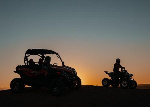Pair riding a 500cc buggy through the rocky Agafay Desert with the Atlas Mountains in the background